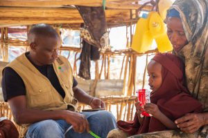 An action against hunger volunteer providing nutritious food to a mother and her child in somalia