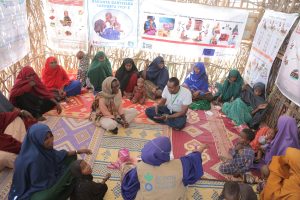 A group of somallian women and their circle sitting in a circle at a menstrual hygiene workshop run by action against hunger