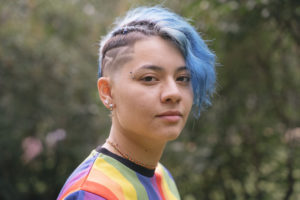 Young cheerful woman with expression of sadness and blue short hair.